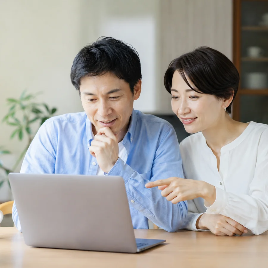 ノートパソコンを見ながら、施工について相談する笑顔のご夫婦