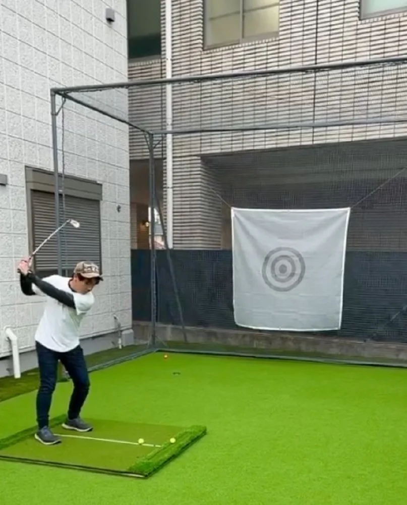 自宅の屋外に設置した防球ネットと人工芝の打席で、アイアンを練習している様子