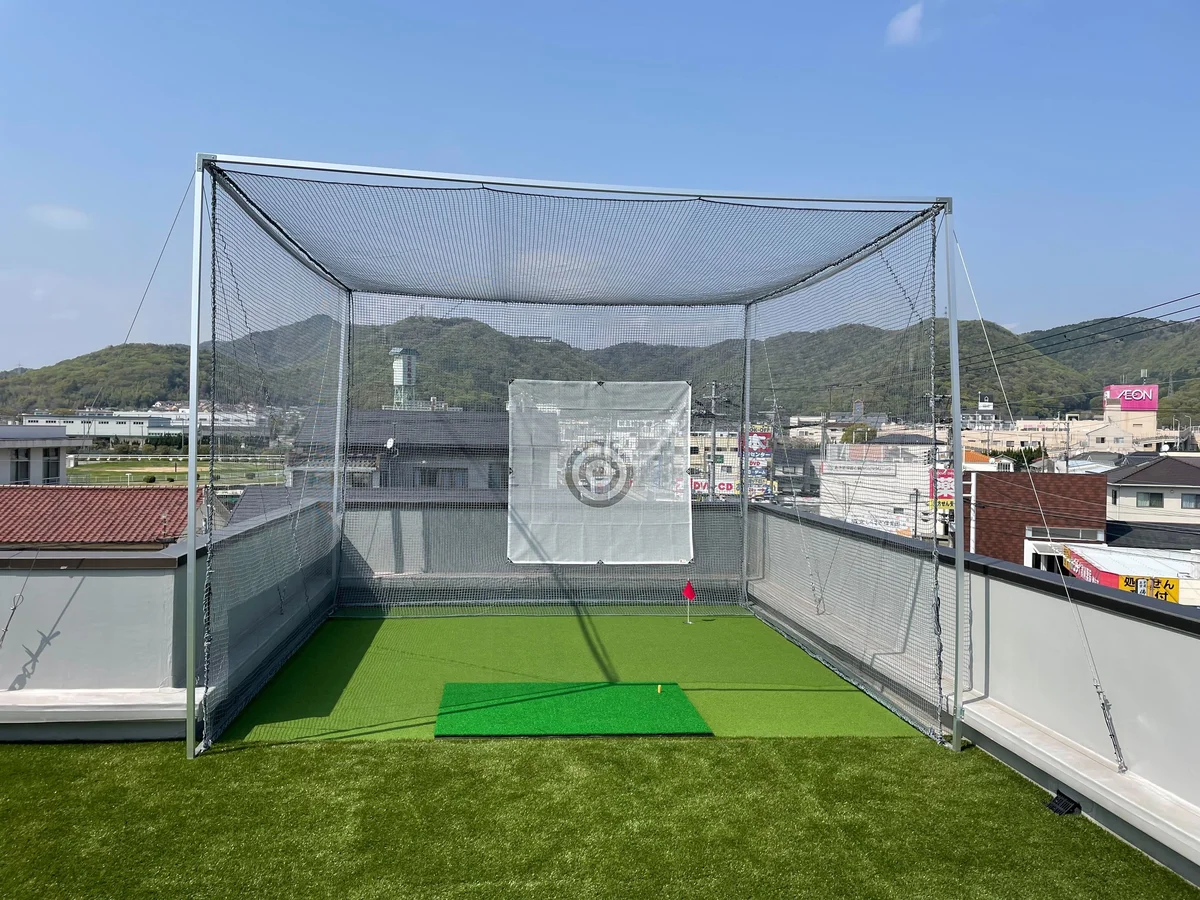 屋上に設置した大型の造作打席練習設備。防球ネットに囲まれた人工芝の打席とティーマット