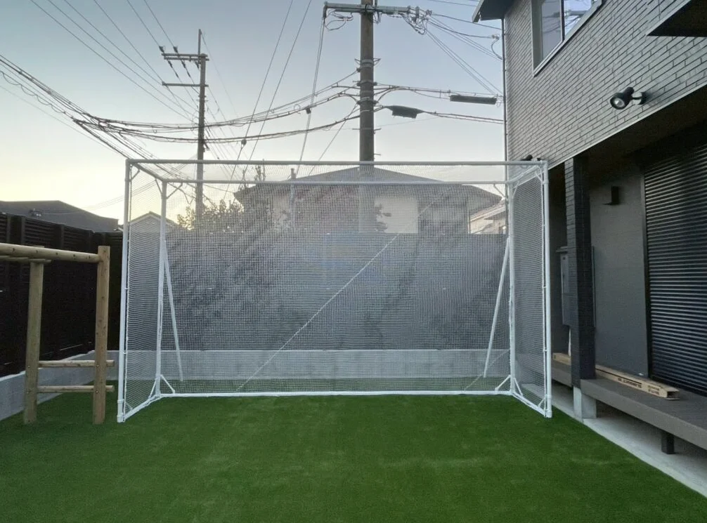 庭に設置した、サッカーゴールとゴルフ打席を兼用できる白いフレームの防球ネット
