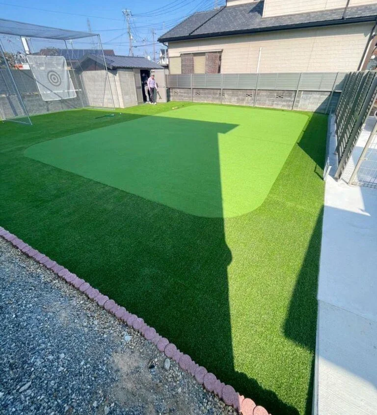 戸建て住宅の庭に施工した、うねりのあるパターグリーンと防球ネット