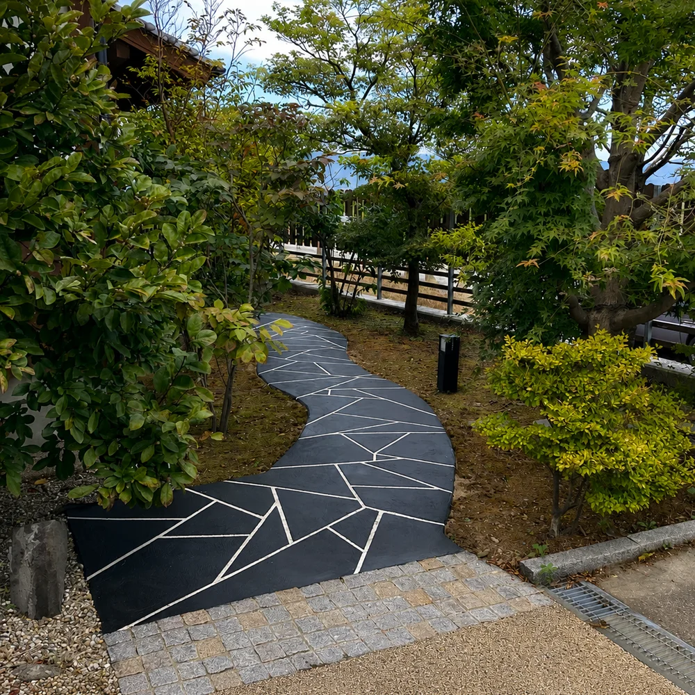 植栽の間を曲がりながら続く、白い目地の入った黒い石材風のTFフロアの小道